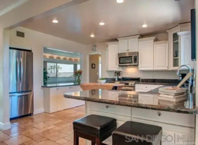 a kitchen with granite countertop a stove sink and microwave