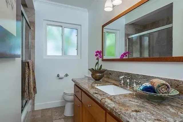a bathroom with a granite countertop sink a toilet and mirror