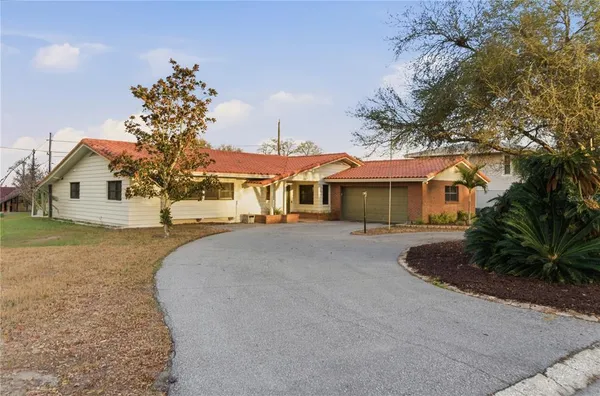 a front view of a house with a garden and trees
