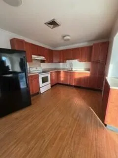 a kitchen with stainless steel appliances wooden floor and a refrigerator