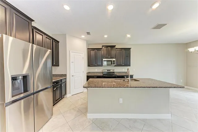 a large kitchen with stainless steel appliances granite countertop a refrigerator a sink a stove a microwave and island