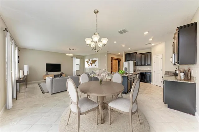 a dining room with furniture a chandelier and kitchen view