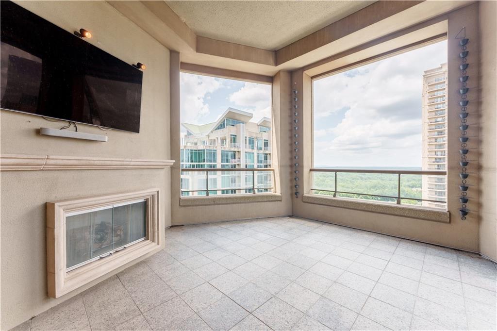 3376 Peachtree Road Northeast, Unit 34A Atlanta, GA 30326 - Photo 8 of 30 a living room with a fireplace a flat screen tv and a floor to ceiling window