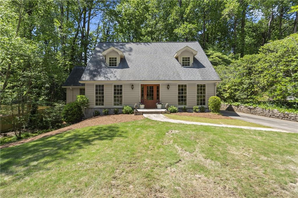 a front view of house with yard and trees in the background