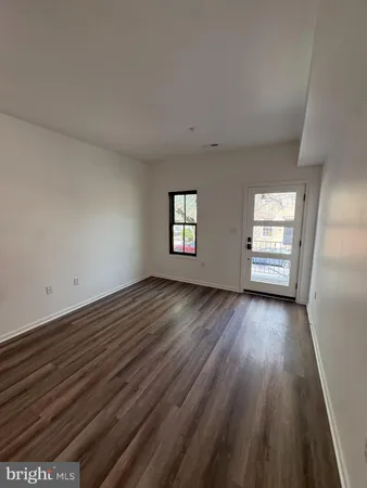 a view of an empty room with window and wooden floor