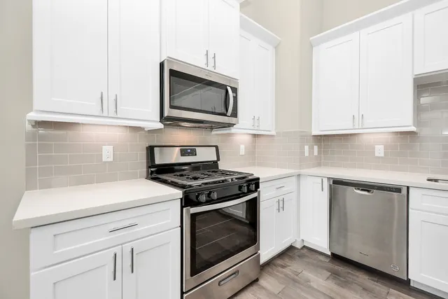 a kitchen with white cabinets and appliances