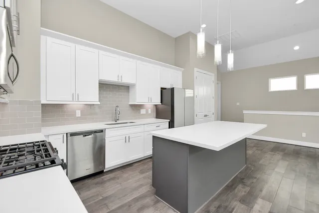 a kitchen with a sink a stove a refrigerator and white cabinets