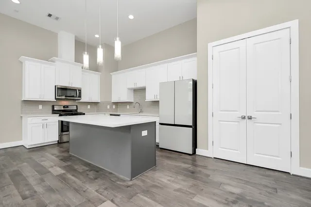 a kitchen with kitchen island a sink a center island stainless steel appliances and cabinets