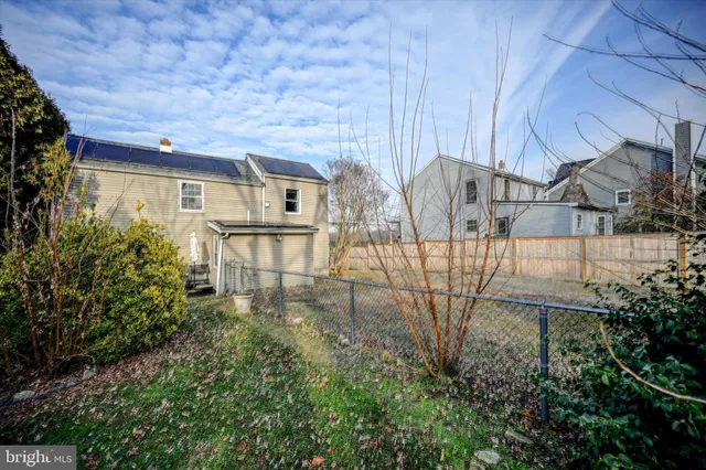 a view of a backyard with table and chairs potted plants and large tree