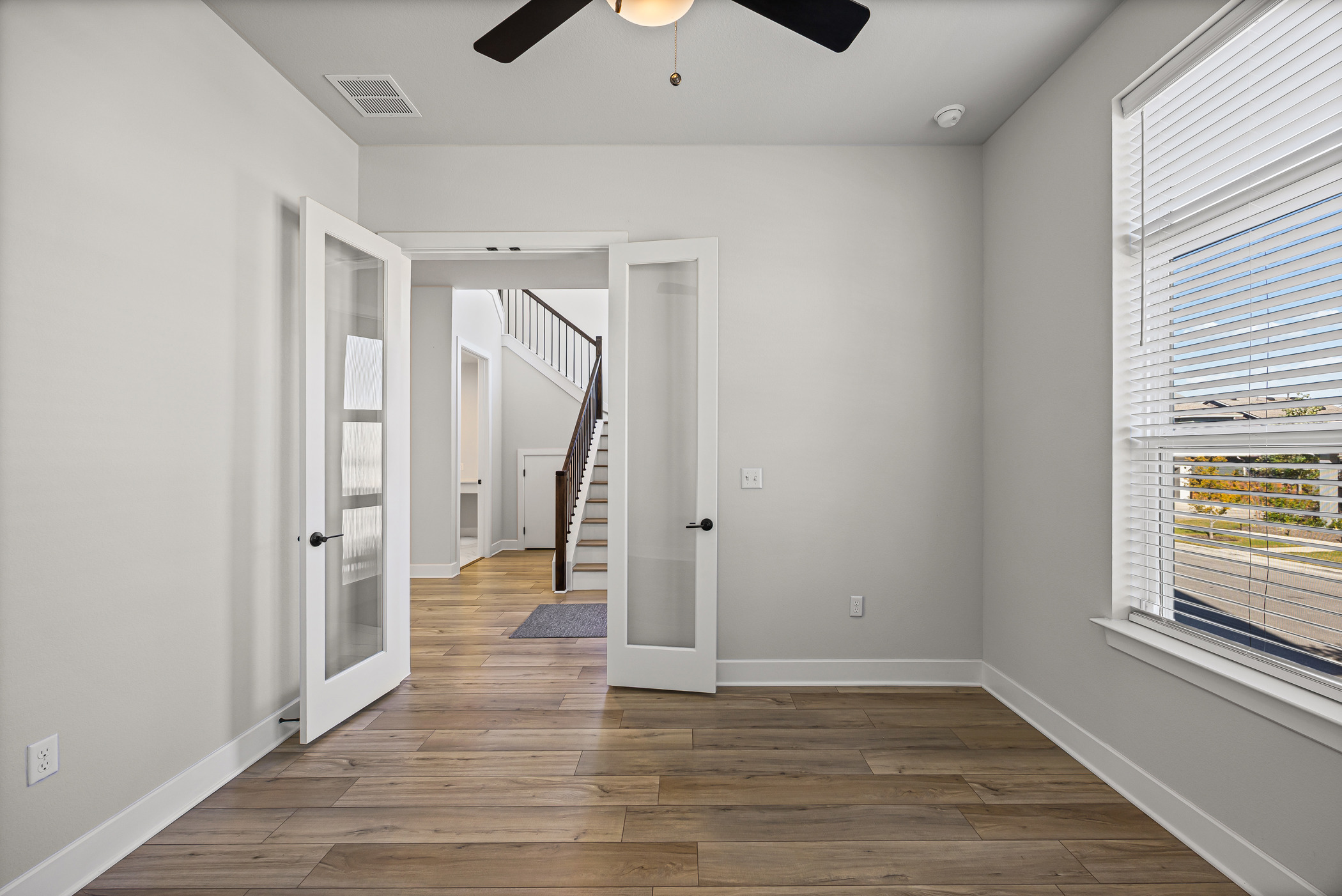 5806 Rangeland Road Austin, TX 78747 - Photo 11 of 34 French doors open into a versatile space featuring resilient hardwood flooring and a functional ceiling fan.