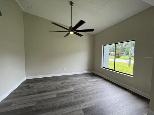 a view of an empty room with a window and wooden floor