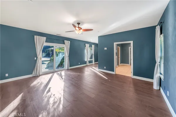 an empty room with wooden floor fan and windows