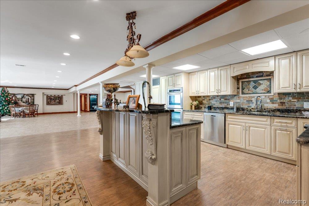 3543 Cedar Brook Drive Rochester, MI 48309 - Photo 49 of 99 Spacious open-concept area featuring a full kitchen with cream cabinetry, dark countertops, and a mosaic tile backsplash