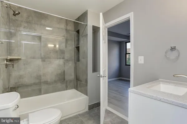a bathroom with a granite countertop bathtub shower sink vanity and toilet