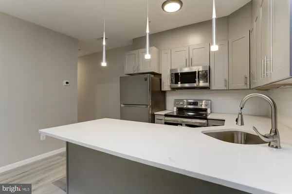 a kitchen with stainless steel appliances a sink a stove a refrigerator a center island and cabinets