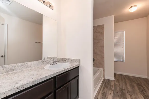 a bathroom with a granite countertop sink a mirror and wooden floor