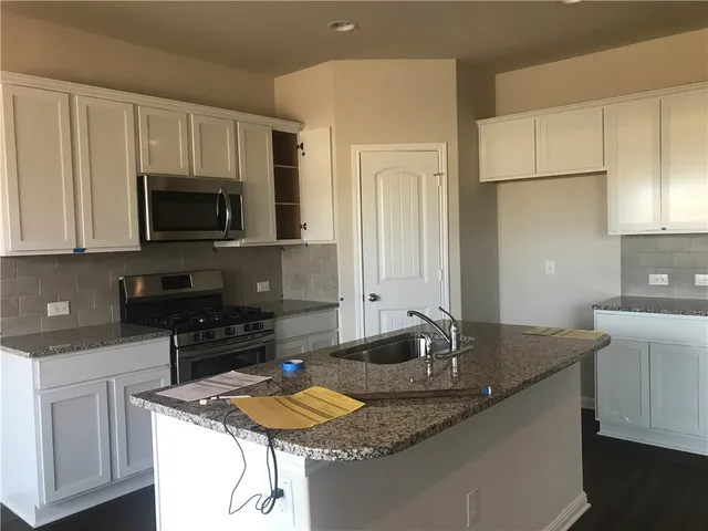 a kitchen with granite countertop a sink a stove and cabinets