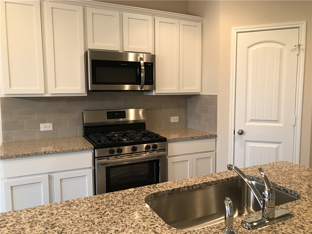 4313 Buffalo Ford Road Georgetown, TX 78628 - Photo 18 of 36 a kitchen with granite countertop a sink and a stove top oven