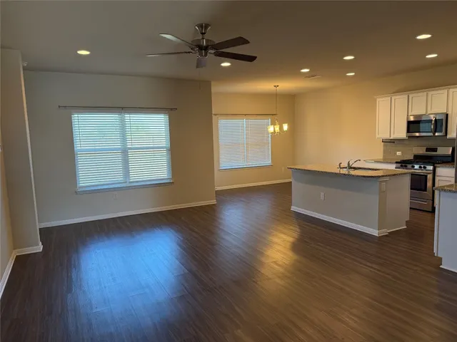 an open kitchen with kitchen island wooden floors and stainless steel appliances