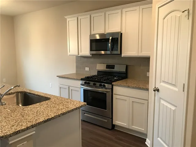 a kitchen with granite countertop a sink and a stove top oven