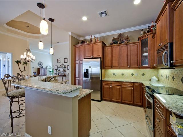 5066 Rustic Oaks Circle Naples, FL 34105 - Photo 7 of 12 a kitchen with granite countertop a sink a counter top space appliances and cabinets