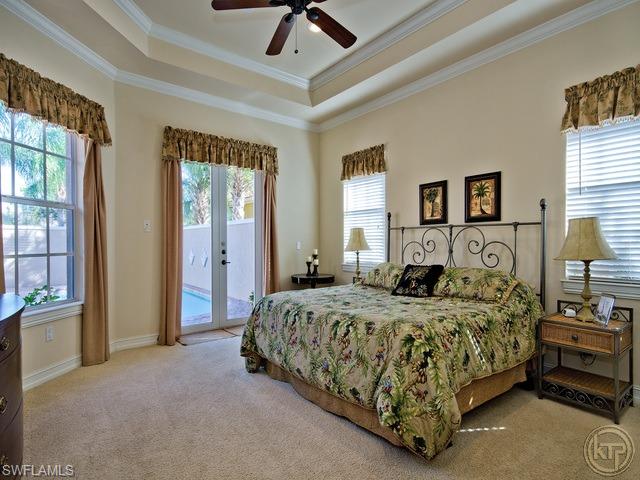 5066 Rustic Oaks Circle Naples, FL 34105 - Photo 8 of 12 a bedroom with a large bed and a chandelier fan