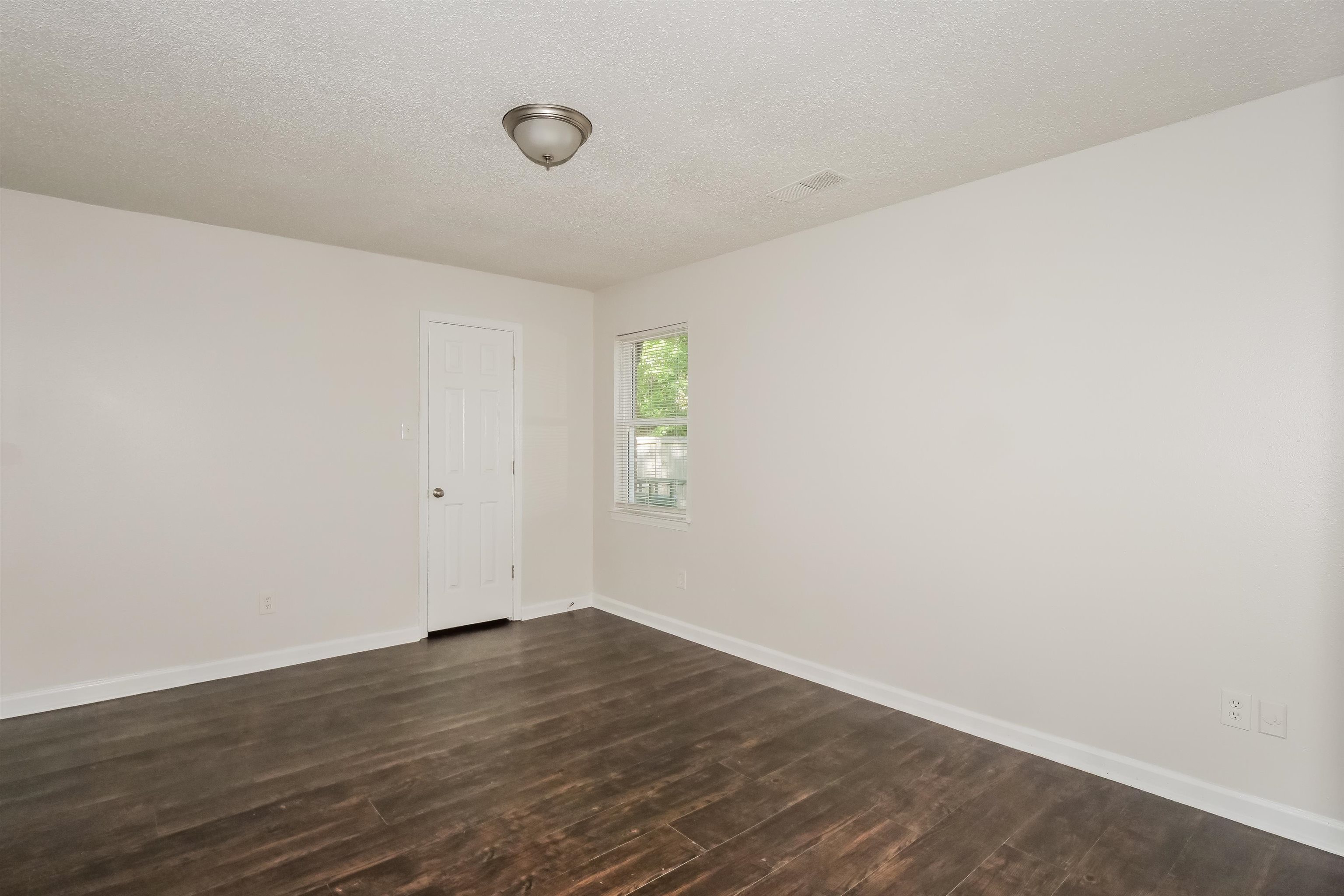 3824 Windermere Road Memphis, TN 38128 - Photo 7 of 16 a view of an empty room with wooden floor and a window