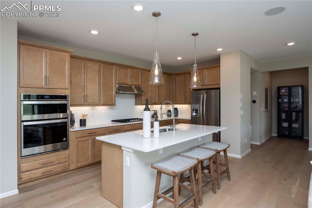 631 Felicity Loop Castle Rock, CO 80109 - Photo 6 of 33 a kitchen with stainless steel appliances a dining table chairs sink and cabinets