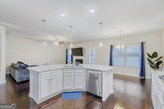 a large white kitchen with a stove and wooden floor
