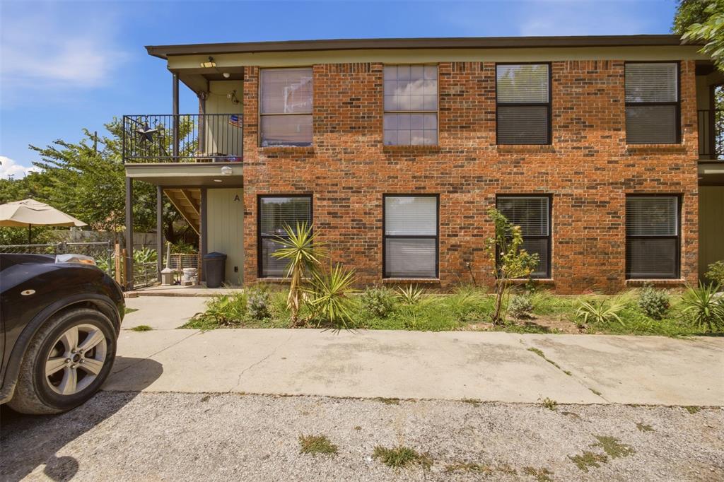 908 Isbell Road, Unit D Fort Worth, TX 76114 - Photo 1 of 27 Two-story brick exterior with black-framed windows, a second-story balcony with dark railings, and ground-level landscaping