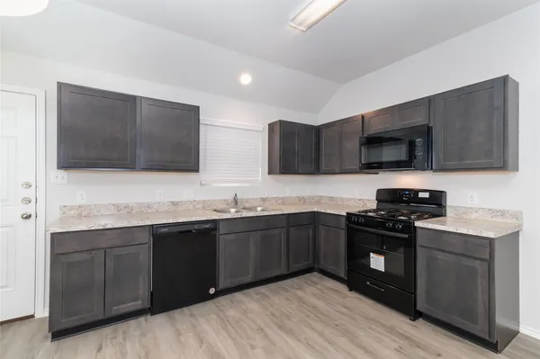 a large kitchen with stainless steel appliances kitchen island granite countertop a stove top oven a sink dishwasher a dining table and chairs with wooden floor