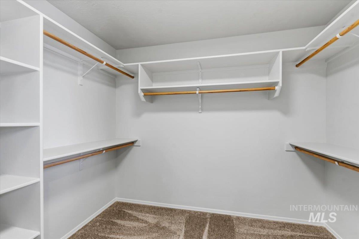 12310 West Hidden Point Drive Star, ID 83669 - Photo 17 of 48 Walk-in closet In the master suite featuring built-in shelving, white walls, multiple hanging rods, and neutral-toned carpet flooring
