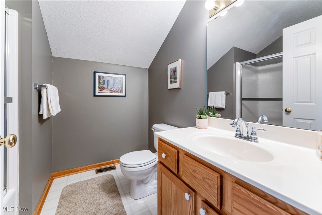 2444 Charing Cross Road Northwest Canton, OH 44708 - Photo 29 of 40 Bathroom with walk in shower, lofted ceiling, vanity, and toilet