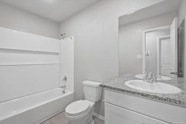 a bathroom with a granite countertop sink a toilet and bathtub