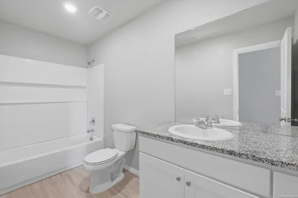 a bathroom with a granite countertop sink a toilet and bathtub
