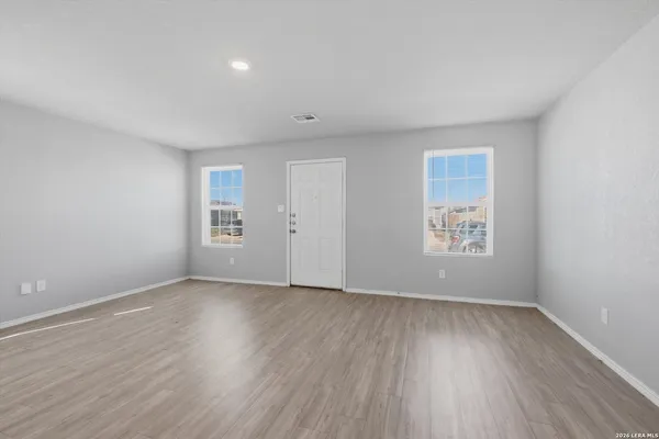 a view of an empty room with wooden floor and a window