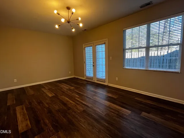 a view of an empty room with window and wooden floor