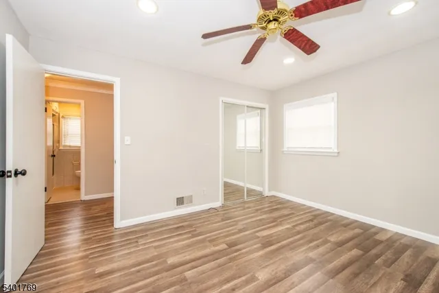 an empty room with wooden floor chandelier fan and windows