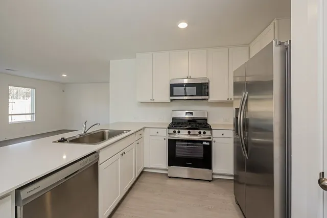 a kitchen with a sink a microwave a refrigerator and cabinets