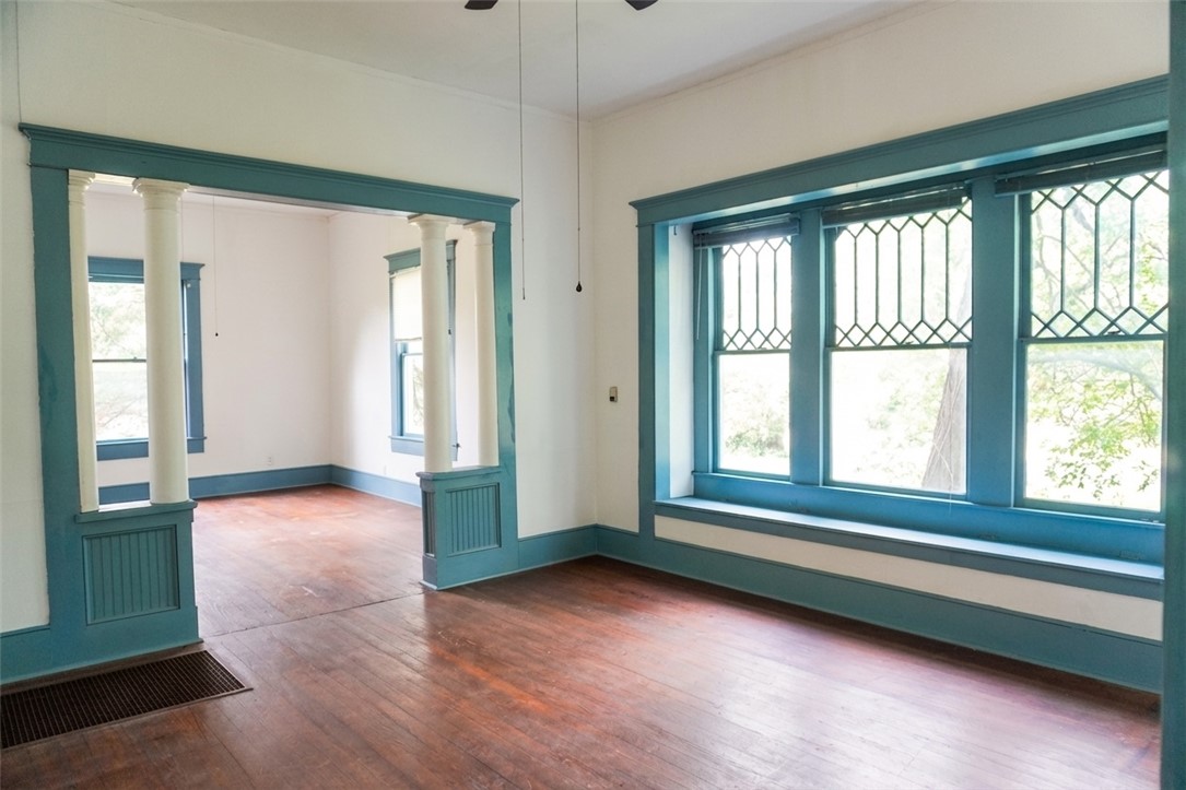 608 West 27th Street Bryan, TX 77803 - Photo 8 of 39 Dining and living rooms featuring decorative columns, dark wood-style flooring, and baseboards