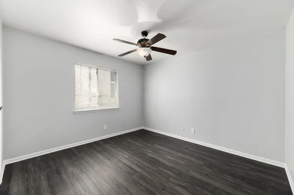 an empty room with wooden floor ceiling fan and windows