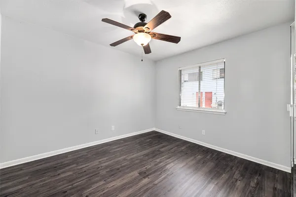 an empty room with wooden floor and ceiling fan