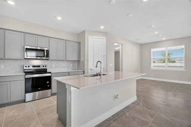 a large white kitchen with stainless steel appliances granite countertop a sink and dishwasher a stove top oven with wooden floor