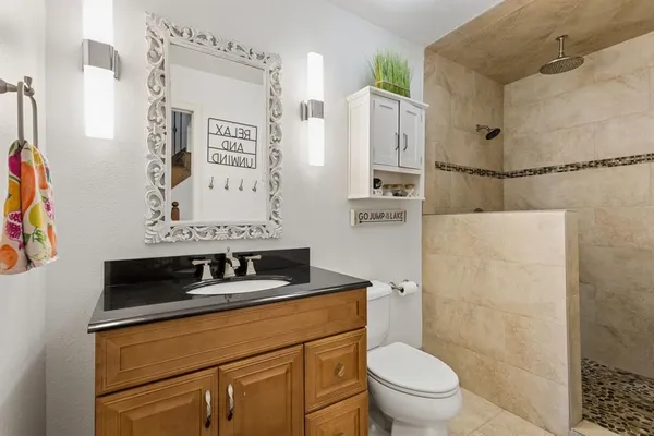 a bathroom with a granite countertop sink toilet and shower