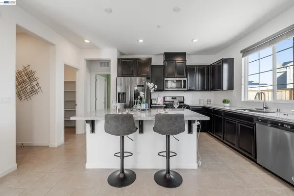 a kitchen with stainless steel appliances kitchen island granite countertop a stove a sink a refrigerator and cabinets