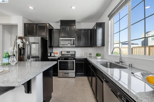 a kitchen with stainless steel appliances granite countertop a sink stove microwave and refrigerator