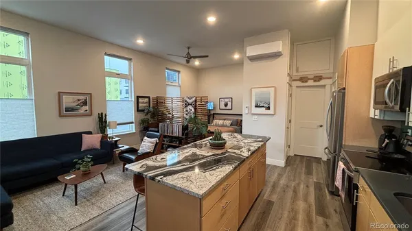 a kitchen with stainless steel appliances granite countertop a stove refrigerator and a couch