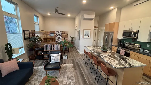 a kitchen with stainless steel appliances kitchen island granite countertop a stove a refrigerator a dining table and chairs with wooden floor