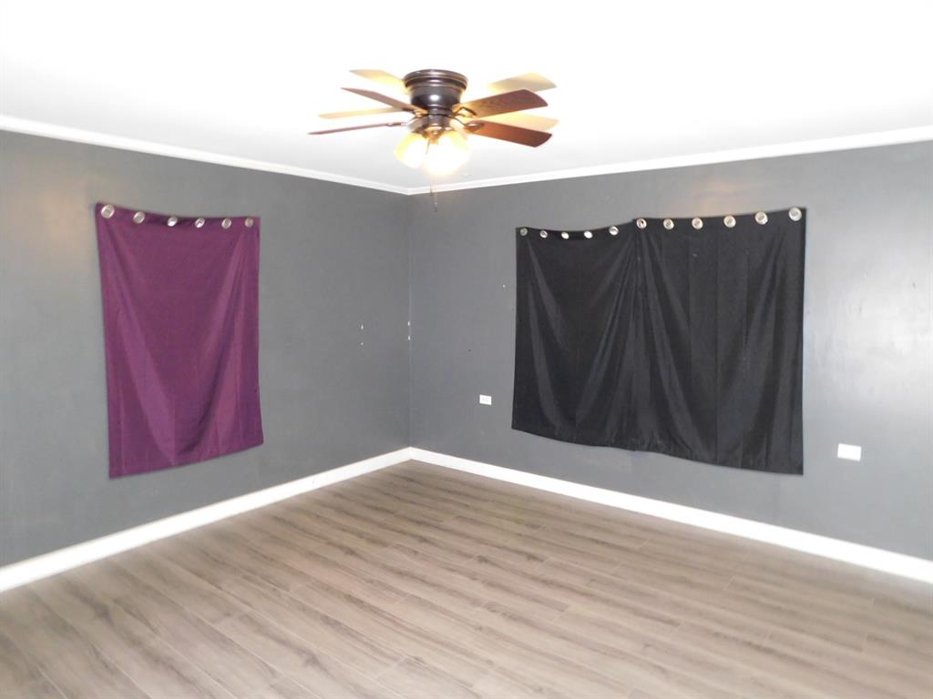 901 North Arkansas Street Springhill, LA 71075 - Photo 20 of 26 Unfurnished room with baseboards, crown molding, wood finished floors, and a ceiling fan