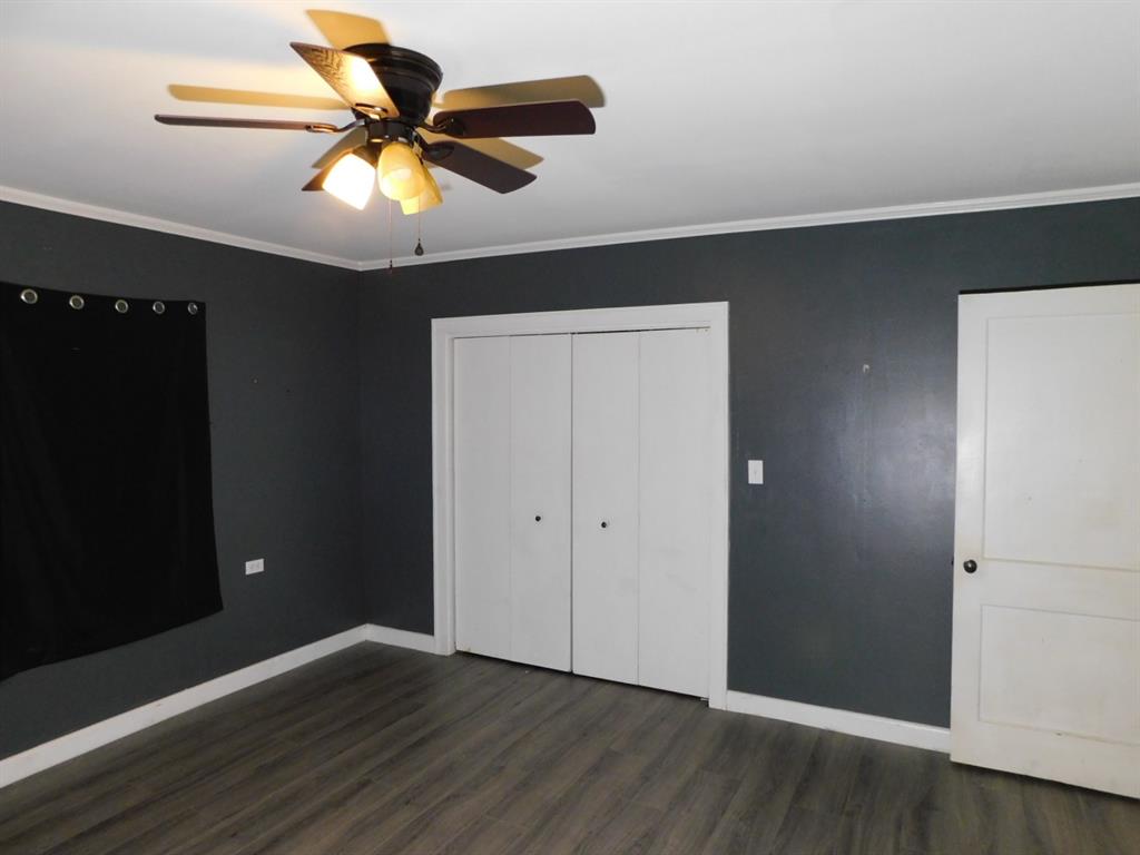 901 North Arkansas Street Springhill, LA 71075 - Photo 21 of 26 Unfurnished bedroom featuring dark wood finished floors, baseboards, a closet, and ornamental molding